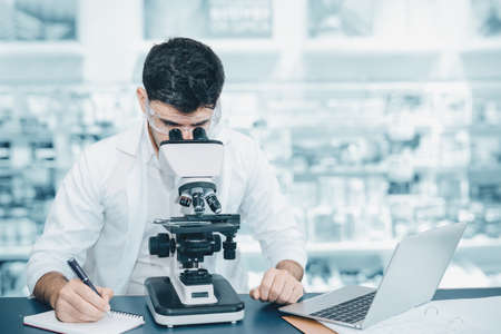 Male Research Medical Scientist Working With Microscope Testing Equipment in Laboratory,...