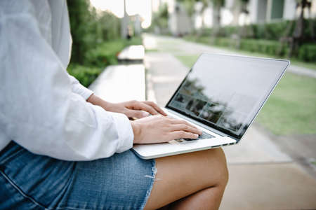 Close-Up of Woman Using Laptop for Business Communication While Sitting on Garden Bench....