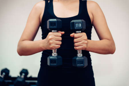 Sport Woman is Exercising in Fitness Gym, Closeup of Attractive Sporty Woman Workout Lifting Weight Dumbbell in Fitness Club. Exercise Wellness Lifestyle and Sport Trainingの写真素材