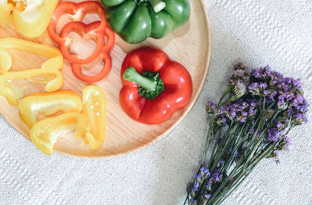 Sweet Pepper Cutting Sliced Preparation for Cooking. Raw Variety Red, Green, Yellow Sweet Peppers Slicing Chopped in Wooden Bowl on Kitchen Table. Raw Organic Sweet Pepper Ready to Eatの写真素材