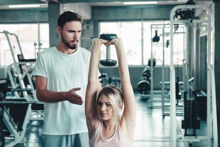 Couple Love Exercising Workout in Fitness Training Room, Young Couple Caucasian Working Out and Exercise Training Together With Dumbbell Equipment in Fitness Club. Fitness Sport Trainer Lifestylesの写真素材