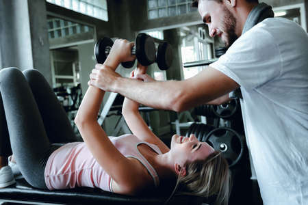 Couple Love Exercising Workout in Fitness Training Room, Young Couple Caucasian Working Out and Exercise Training Together With Dumbbell Equipment in Fitness Club. Fitness Sport Trainer Lifestylesの写真素材