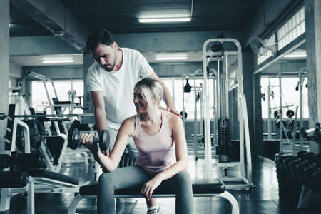 Couple Love Exercising Workout in Fitness Training Room, Young Couple Caucasian Working Out and Exercise Training Together With Dumbbell Equipment in Fitness Club. Fitness Sport Trainer Lifestylesの写真素材