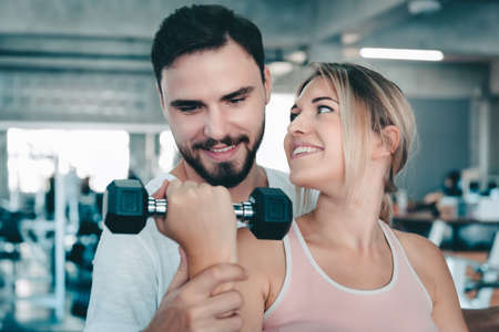 Couple Love Exercising Workout in Fitness Training Room, Young Couple Caucasian Working Out and Exercise Training Together With Dumbbell Equipment in Fitness Club. Fitness Sport Trainer Lifestylesの写真素材