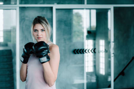 Female Boxer is Training Punch Boxing in Fitness Gym, Portrait of Sport Boxer Woman in Sportswear Exercised Practicing Boxing in Gym Club. Exercising Lifestyles and Fitness Sport Workout Trainingの写真素材