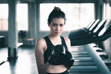 Female Boxer is Training Punch Boxing in Fitness Gym, Portrait of Sport Boxer Woman in Sportswear Exercised Practicing Boxing in Gym Club. Exercising Lifestyles and Fitness Sport Workout Trainingの写真素材