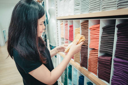 Promotion Sale and Clothes Shopping Concept, Shopaholic Woman is Looking for Choosing Clothes in Shopping Department Store. Attractive Woman Enjoying While Shopping in Mall Shop. Leisure Lifestylesの写真素材