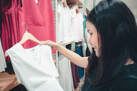 Promotion Sale and Clothes Shopping Concept, Shopaholic Woman is Looking for Choosing Clothes in Shopping Department Store. Attractive Woman Enjoying While Shopping in Mall Shop. Leisure Lifestylesの写真素材