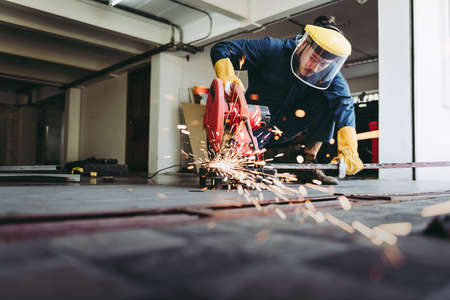 Craftsman Welding is Cutting Steel Work in Fabrication Workshop, Welder Man in Safety Protective Equipments Doing Metalwork in Construction Site. Steel Labor Skill and Workshops Production Conceptの写真素材