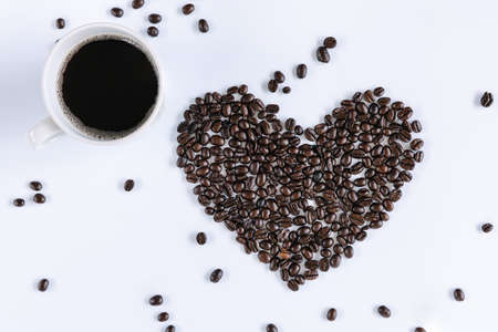 Coffee Cup and Roasted Coffee Beans Heart Shape on White Isolated Background, Closeup of Grain Coffee Ingredients With Hot Coffee Cup Backgrounds. Food and Drink Conceptsの写真素材
