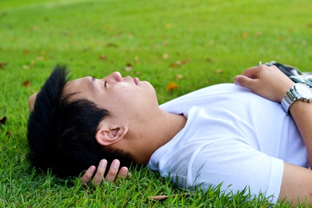 Man sleeping on the grass in the public parkの写真素材