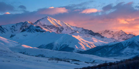 Majestic snow-covered mountain range at sunrise, with pink clouds in the sky.  Peaceful and serene winter landscape.の写真素材