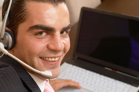 young happy businessman ready to help with a headset and laptop