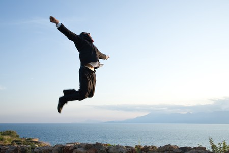 happy businessman jumping high at the hill, motion blur on the manの写真素材