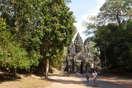 Locals riding bicycles pass the East Gate of Angkor Thom Siem Reap Cambodia.のeditorial素材