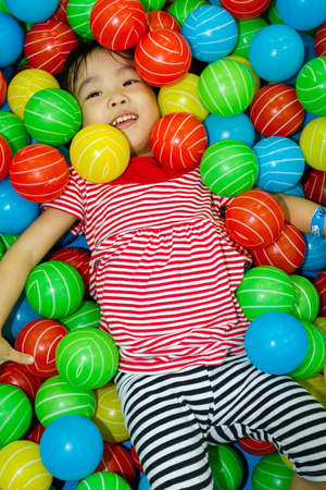 Asian Chinese girl hide in colorful ball pool at indoor playground.の写真素材