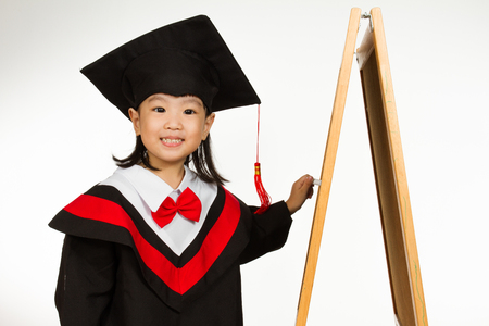Asian Chinese children in graduation gown againts blackboard or chalkboard with formulas in plain isolated white background.の写真素材