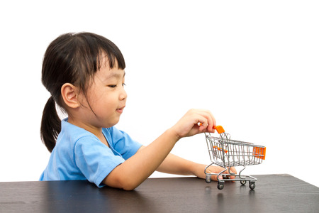 Chinese little girl pushing a toy shopping cart in plain white isolated background.の写真素材