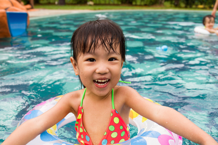 Asian Little Chinese Girl Playing in Swimming Pool with Swimming Circleの写真素材