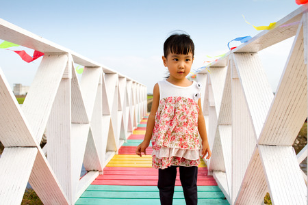 Asian Little Chinese Girl Standing on an Wooden Bridge in Small Villageの写真素材