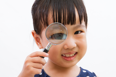 Asian Little Chinese Girl Holding Magnifying Glass isolated on White Backgroundの写真素材
