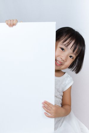 Asian Little Chinese Girl Holding a White Blank in isolated White Backgroundの写真素材