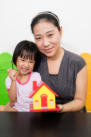 Asian Mother and Little Chinese Girl Holding Key for Property Concept at Playgroundの写真素材