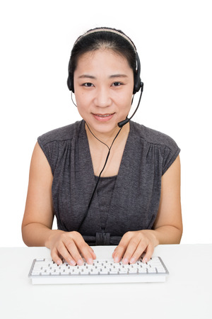 Asian Woman with Headset Using Keyboard in Isolated White Backgroundの写真素材