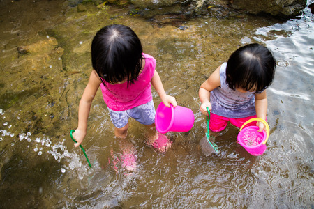Asian Little Chinese Girls Playing in Creek in the Forestの写真素材