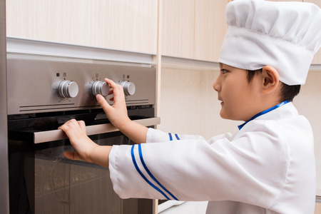 Asian Chinese Boy in white chef uniform Baking Cookies at Homeの写真素材