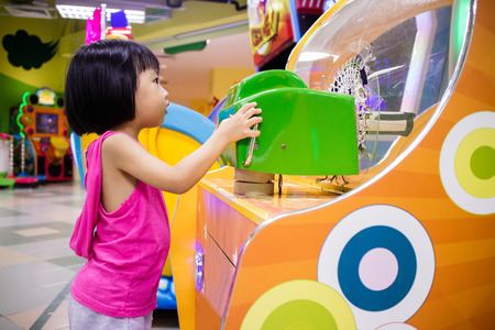 Asian Little Chinese Girl Playing Arcade Game Machine at a indoor Amusement Playgroundの写真素材