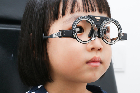 Asian Little Chinese Girl Doing Eyes Examination in isolated White Backgroundの写真素材