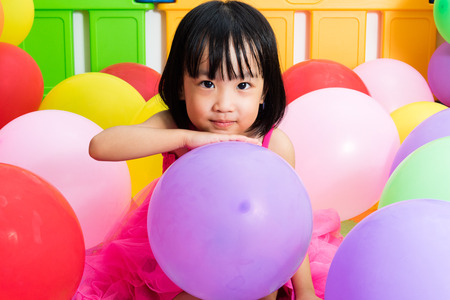 Asian Little Chinese Girl Playing with Colorful Balloons in Indoor Playgroundの写真素材