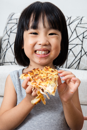 Asian Little Chinese Girl Eating Pizza at Homeの写真素材
