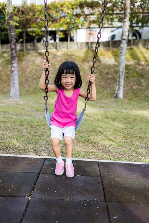 Asian Chinese little girl on swing in playground outdoor.の写真素材