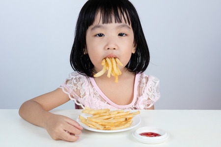 Asian Chinese little girl Refusing Eating French fries with clean isolated background.の写真素材