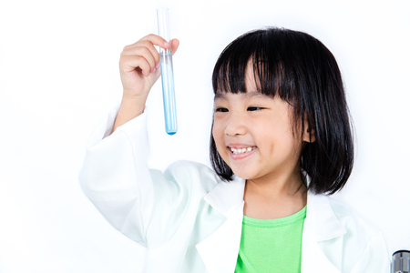 Smiling Asian Chinese Little Girl Examining Test Tube With Uniform in isolated white background.の写真素材