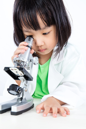 Asian Chinese Little Girl Working With Microscope in isolated white background.の写真素材