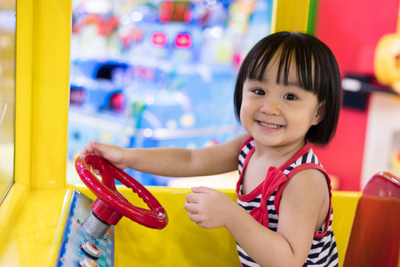 Happy Asian Chinese Little Girl Driving Toy Bus at indoor playground.の写真素材