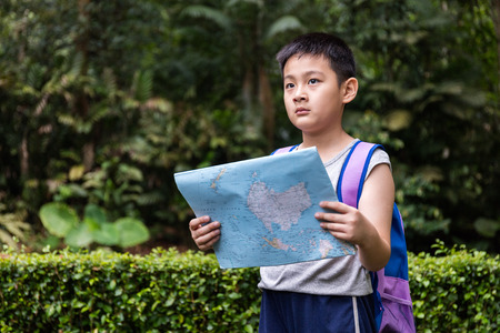 Asian Chinese little boy holding map in the forest searching for direction.の写真素材
