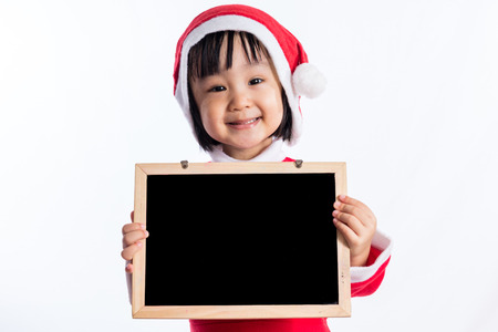 Asian Chinese little girl in santa costume holding blank message board in isolated white backgroundの写真素材