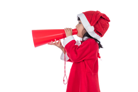 Asian Chinese little santa girl holding loudspeaker shouting in isolated white background.の写真素材
