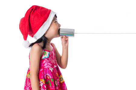 Asian Chinese little girl wearing santa hat holding tin can phone in isolated white background.の写真素材