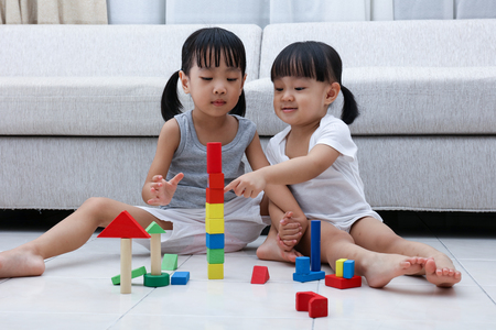 Asian Chinese little sisters playing blocks on the floor in the living room at home.の写真素材
