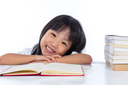 Smiling Asian Chinese little girl reading book in isolated white background.の写真素材