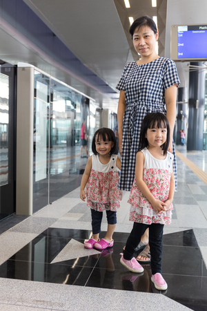 Asian Chinese mother and daughters waiting for transit at MRT station in Kuala Lumpur, Malaysia.の写真素材