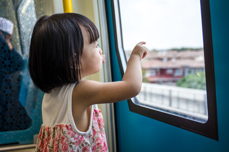 Asian Chinese little girl inside a MRT transit looking far way beside the window.の写真素材