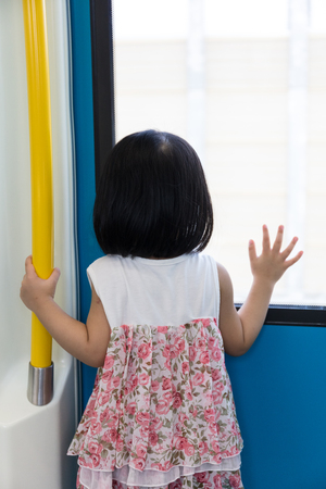 Asian Chinese little girl inside a MRT transit looking far way beside the window.の写真素材