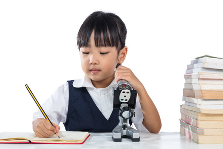 Asian Chinese little girl wearing school uniform with microscope in isolated white background.の写真素材