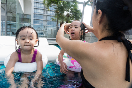 Asian Chinese family playing at the outdoor swimming pool on vacation during summertime.の写真素材